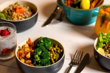 Delicious colorful bowls of salad and fresh beverages on a white table, perfect for healthy dining.